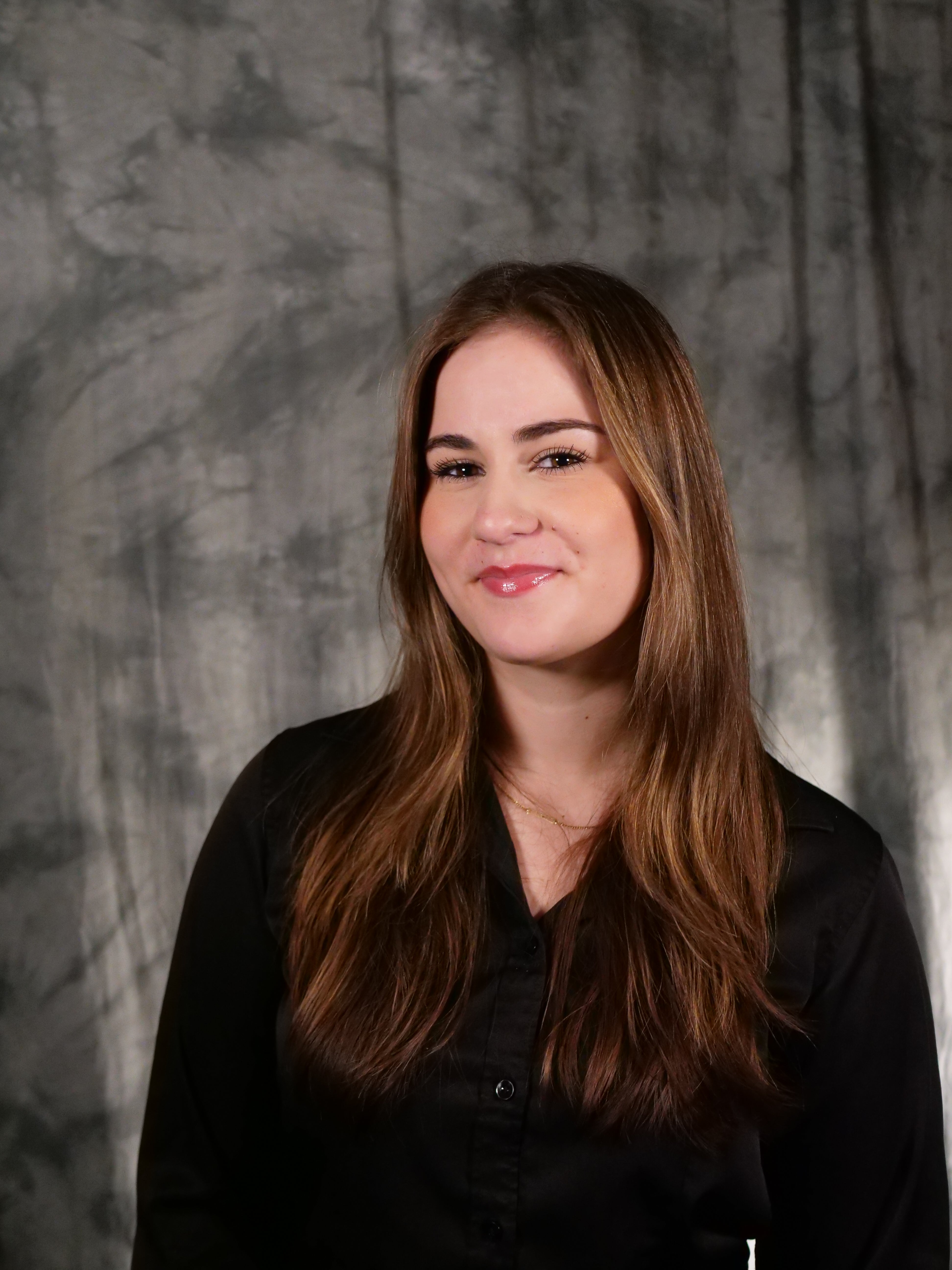 College-aged female student, long brown hair with highlights, dark eyes, smiling, black button up