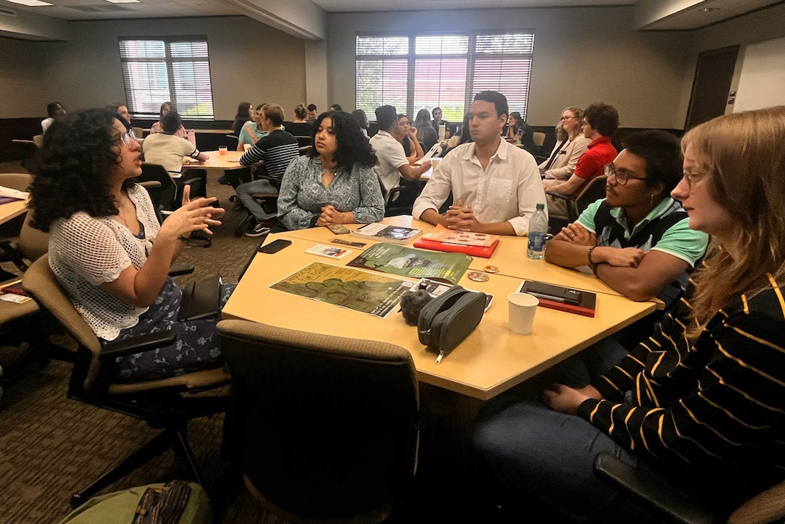 "Five Service Scholars around a table engage in conversation