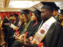 Students in caps and gowns smile at the start of the cultural gradaution ceremony