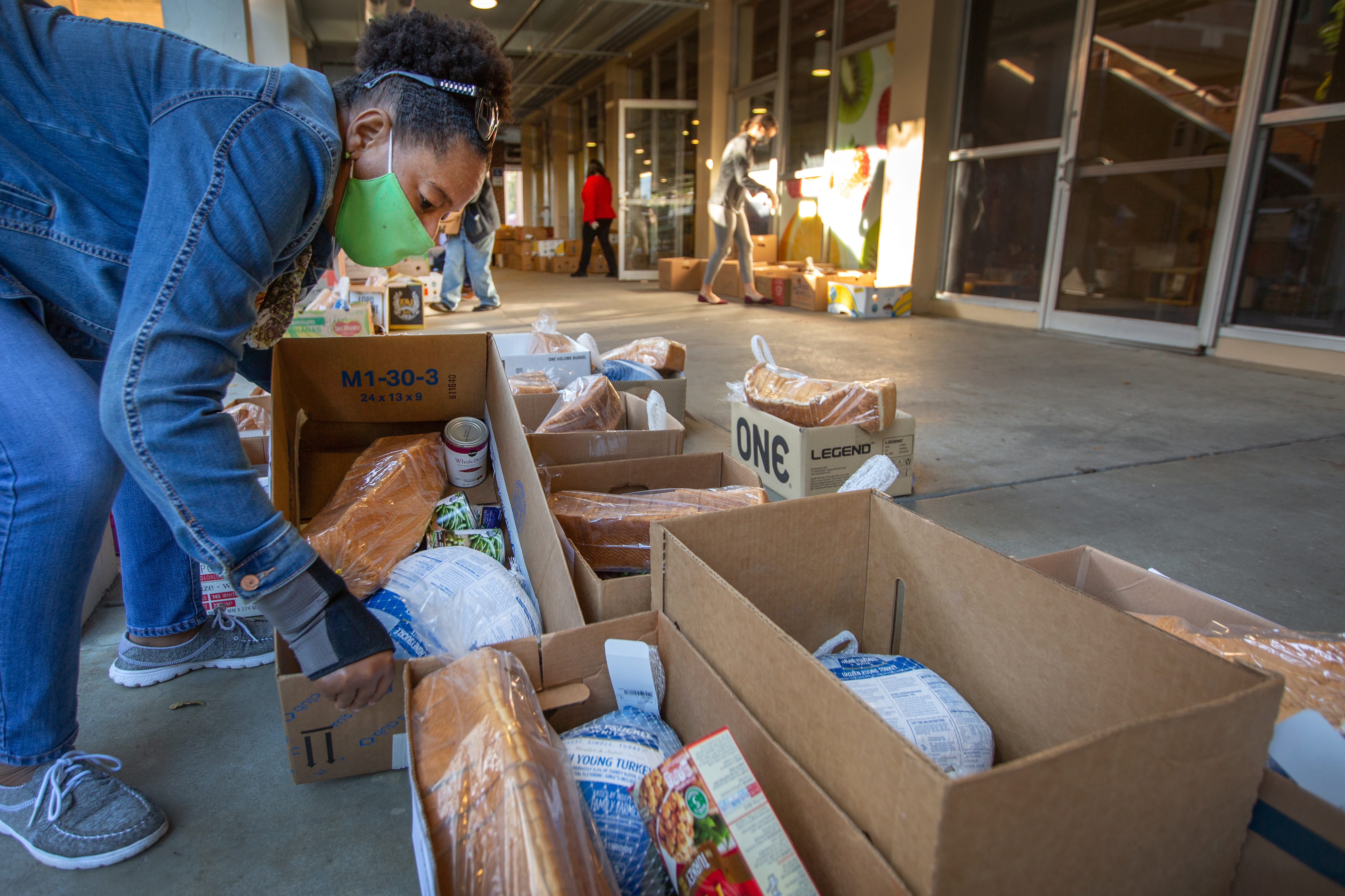 A volunteer prepares a box packed with a turkey and multiple Thanksgiving sides