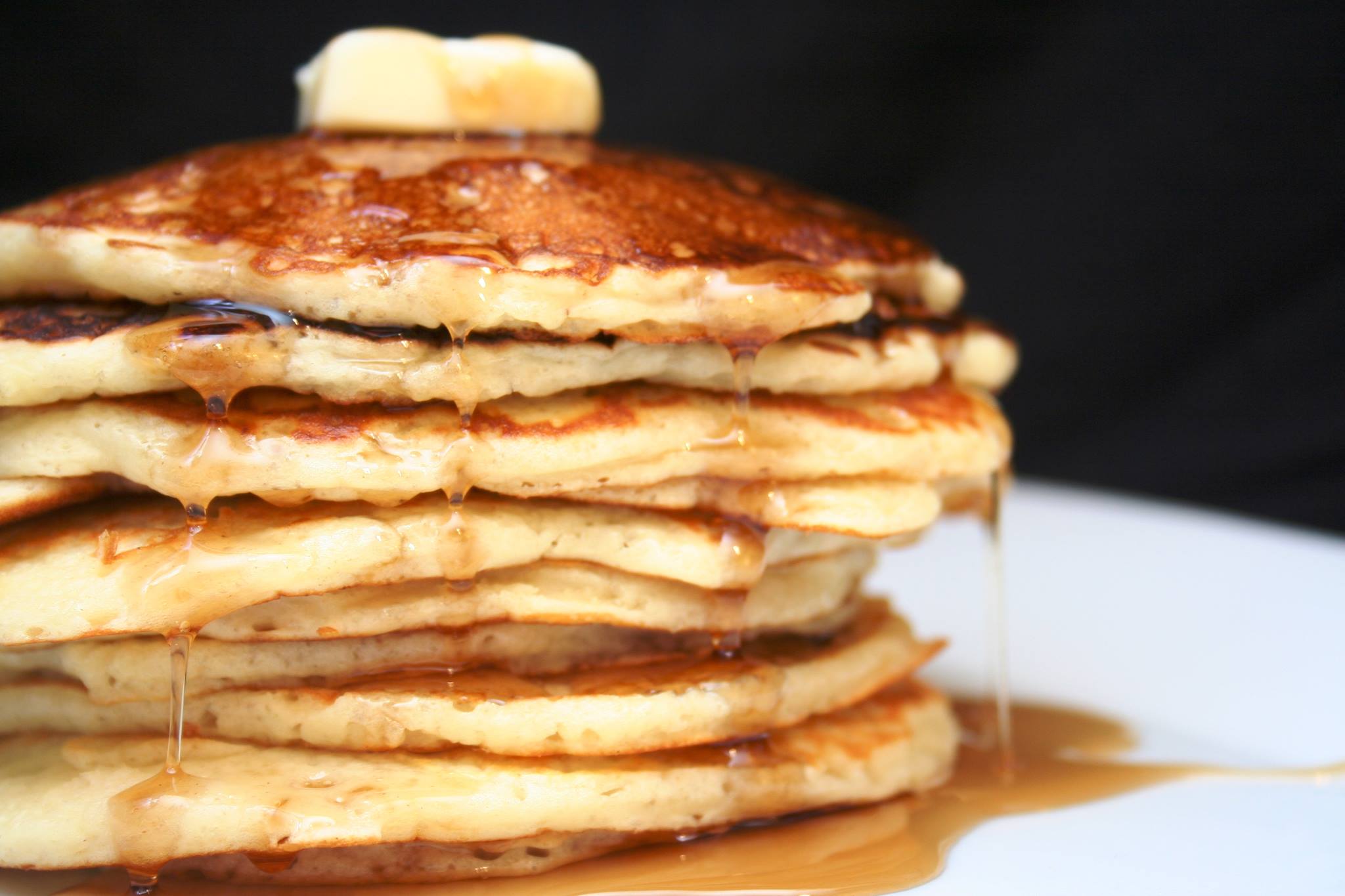 A stack of pancakes with butter and maple syrup on top