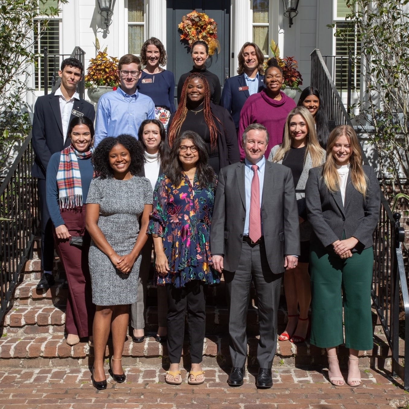 A group of students and staff pose on the front steps of the President's House