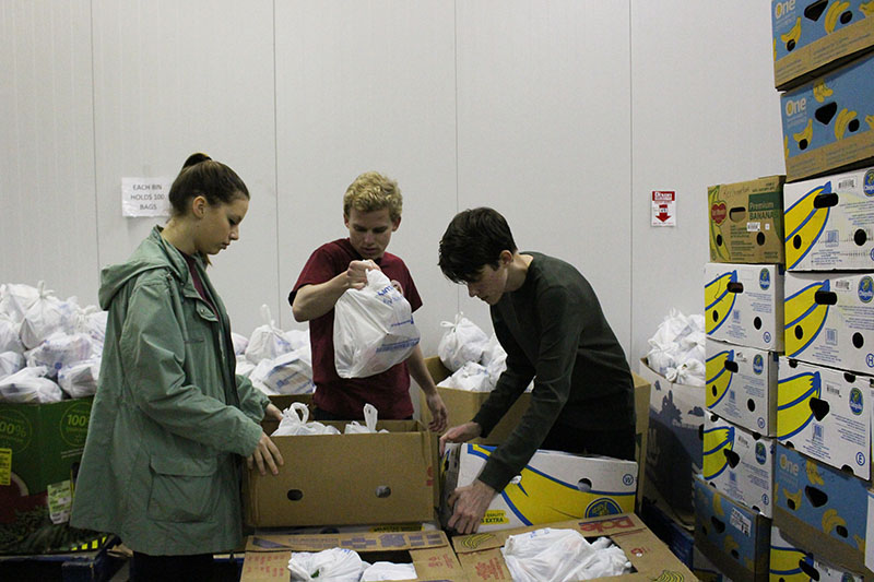 Students sorting and organizing food items into boxes.