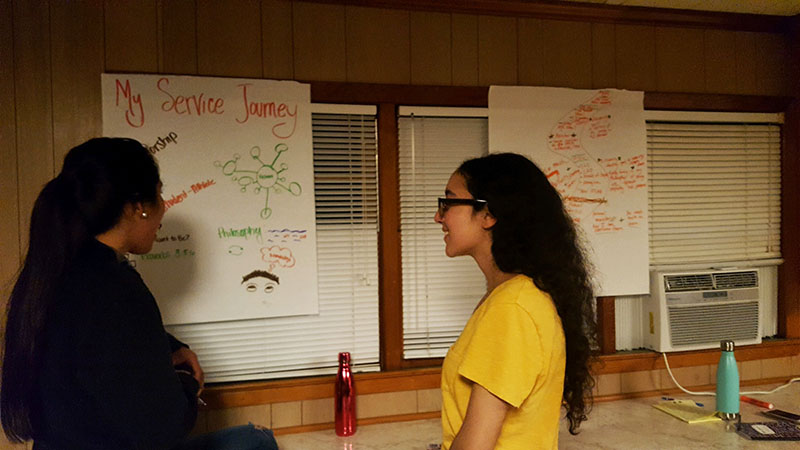 A pair of students reflecting on their service journey poster.