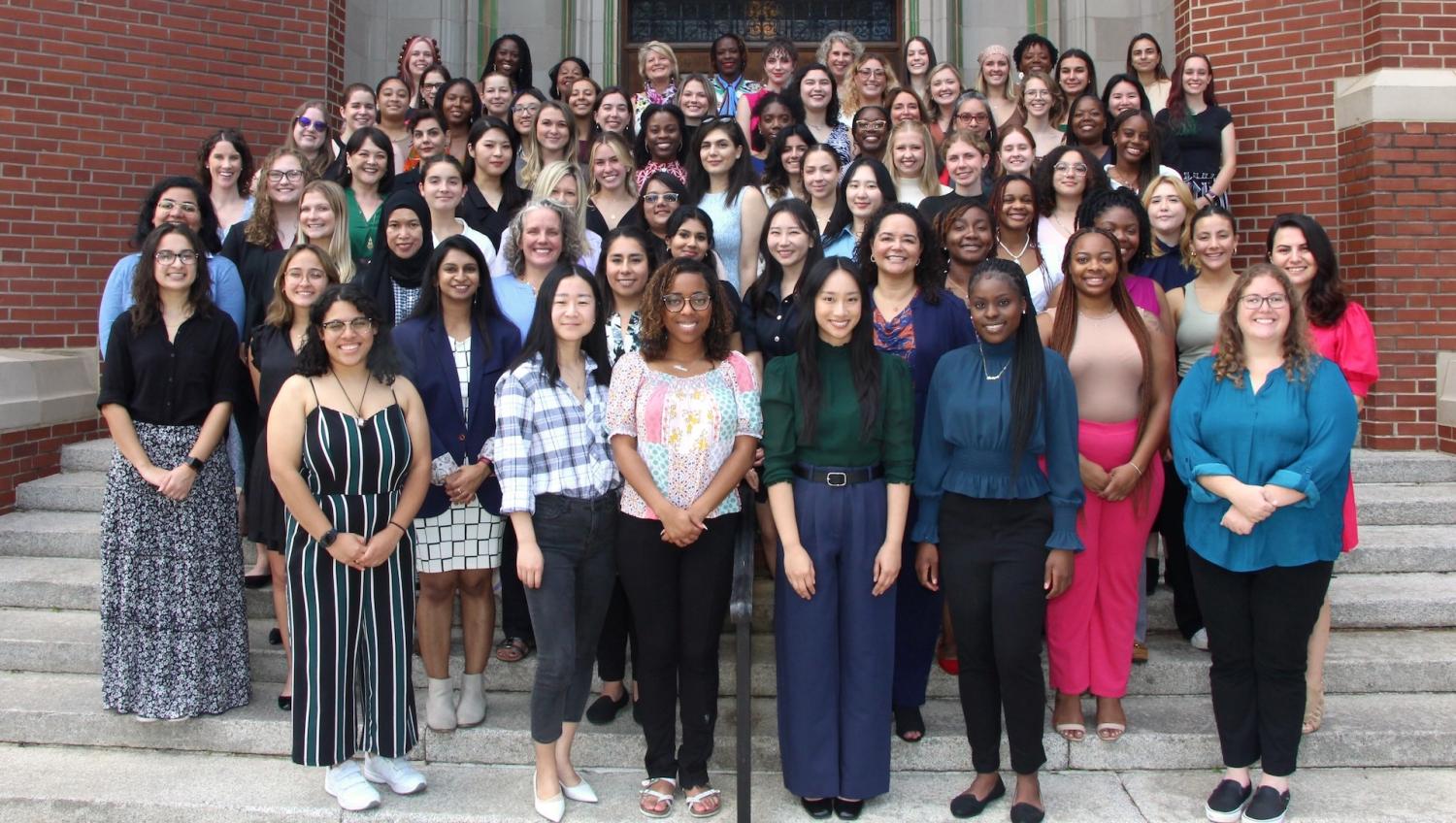 "A large group of women standing on the steps of a university building."