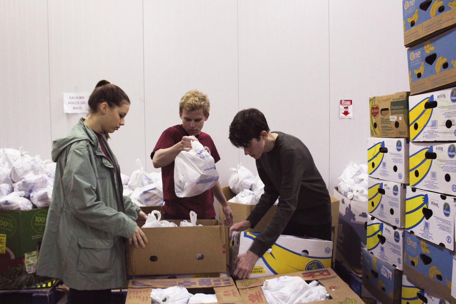 Three students sort food at Second Harvest of the Big Bend during a pre-remote community engagement program. 